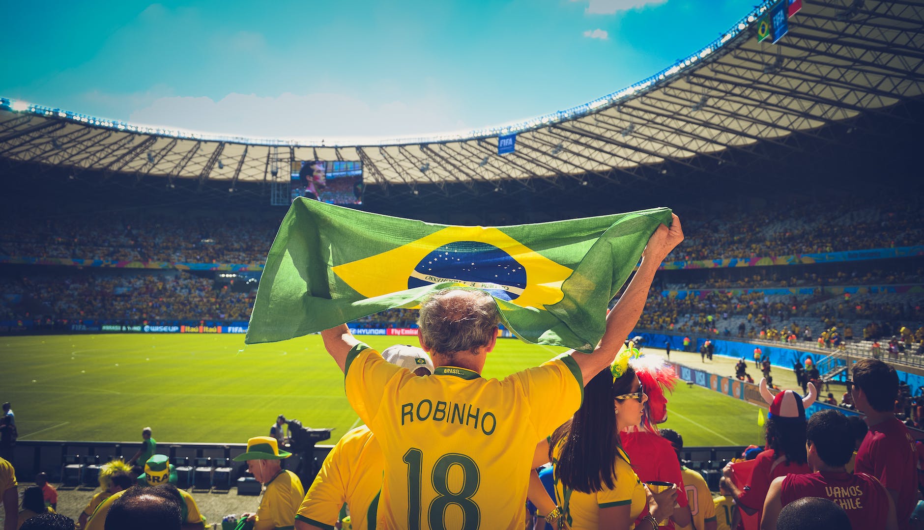 man raising brazil flag inside football stadium